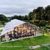 Exterior de una carpa tipo invernadero para un evento en el jardín, con paredes de cristal e iluminación nocturna