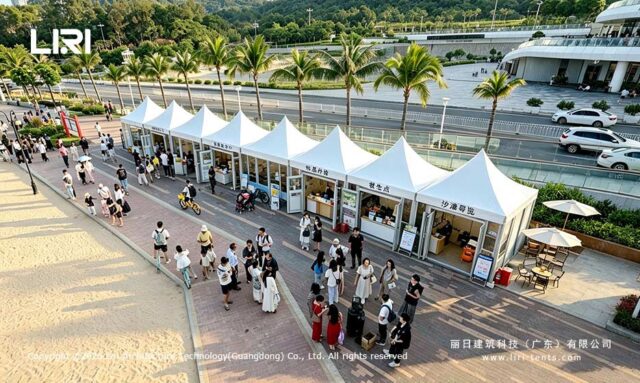 Tiendas modulares en forma de pagoda, unidas entre sí, a lo largo de un paseo bordeado de palmeras